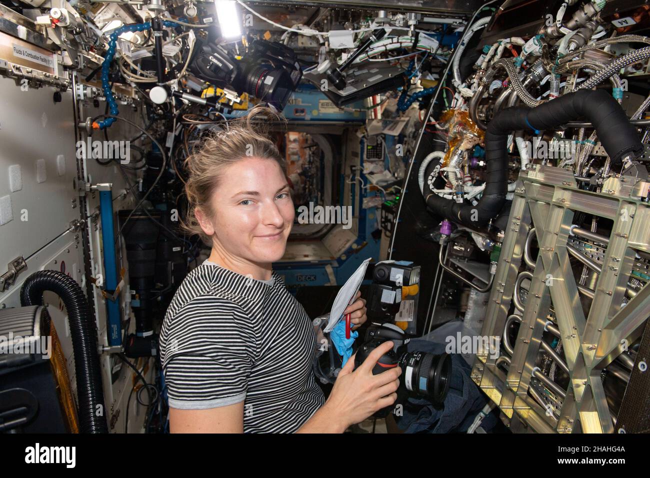 ISS - 04 December 2021 - NASA astronaut and Expedition 66 Flight Engineer Kayla Barron is pictured inspecting and photographing components inside the Stock Photo