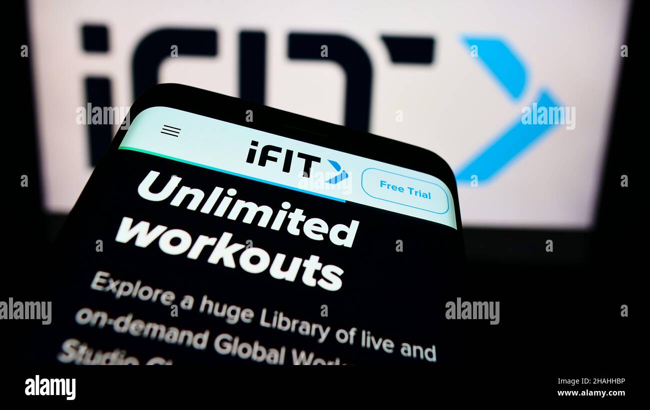 Smartphone with website of US fitness company iFIT Inc. on screen in front of business logo. Focus on top-left of phone display. Stock Photo