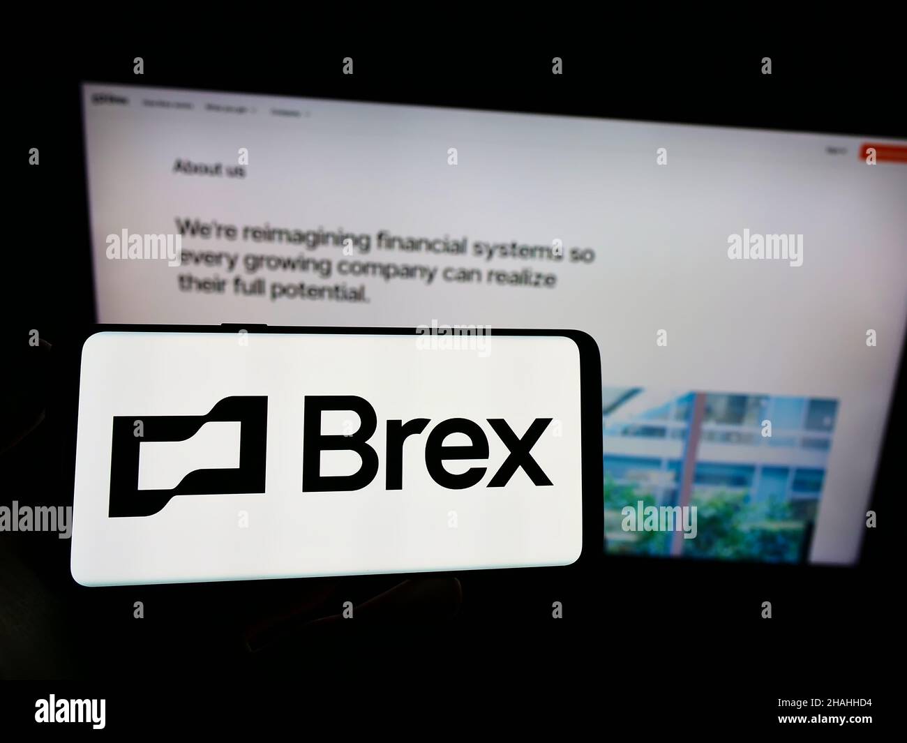Person holding cellphone with logo of American financial technology company Brex Inc. on screen in front of webpage. Focus on phone display. Stock Photo