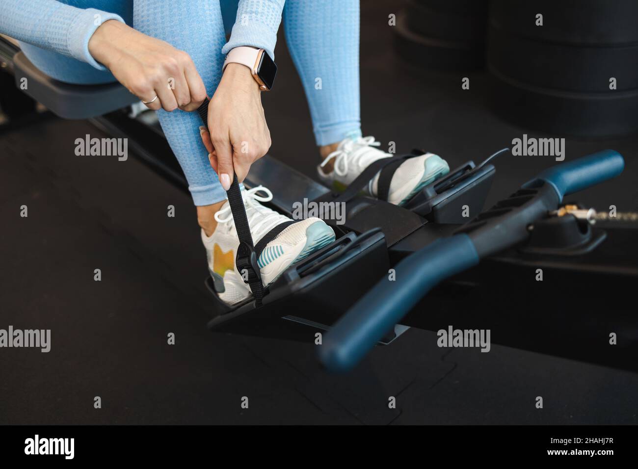 Athletic woman fixes his legs with straps on the rowing machine Stock Photo