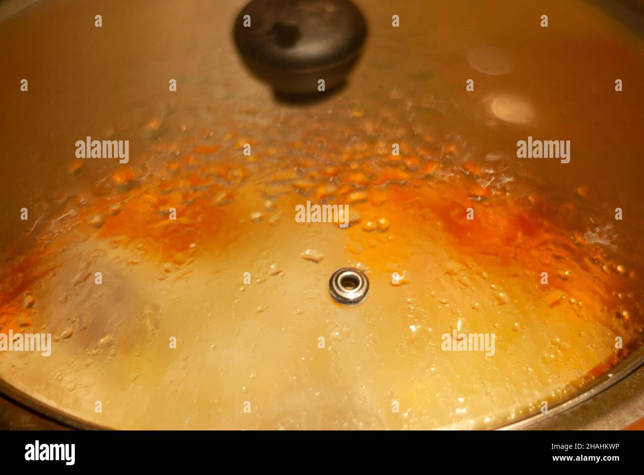 Steam condensation in covered kitchen pot transparent to the fire cooking Stock Photo