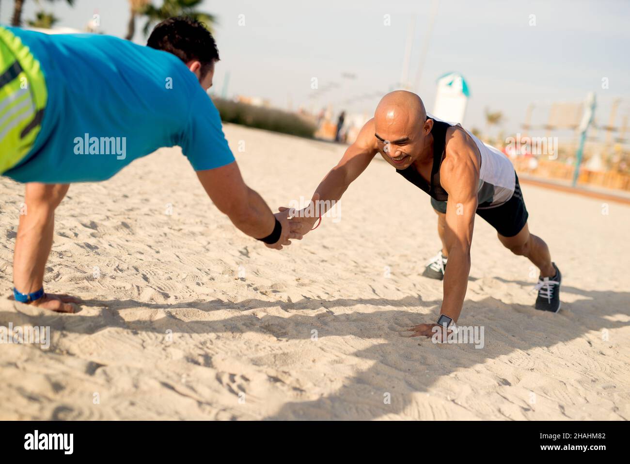 Two handsome athletes working out push ups exercise together at beach ...