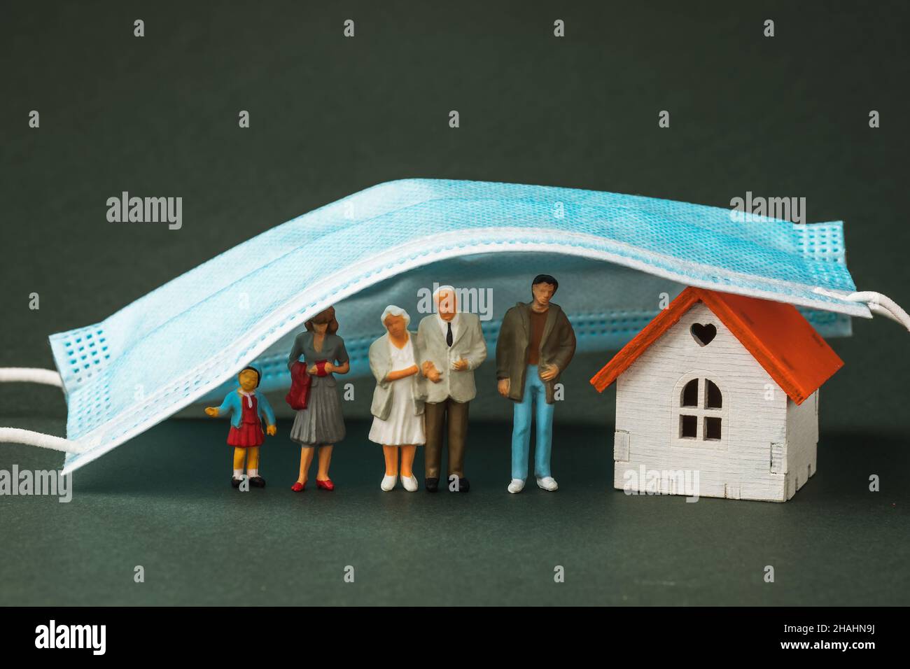 Plastic toy men and a house under a medical mask, the concept of lockdown Stock Photo