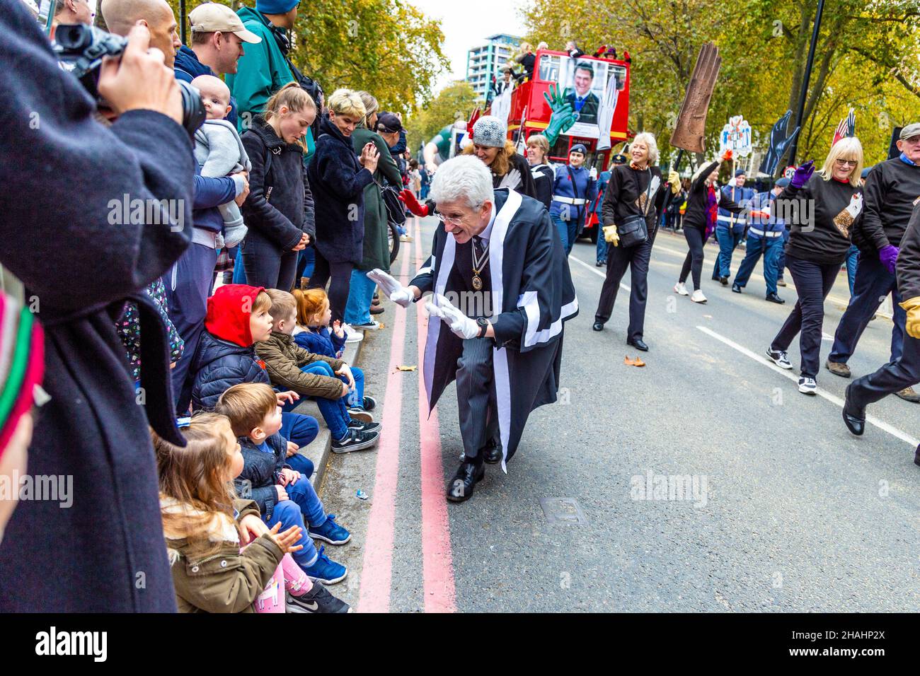 13 November 2021, London, UK - Lord Mayor's Show, man greeting children sitting on the curbside, watching the parade Stock Photo
