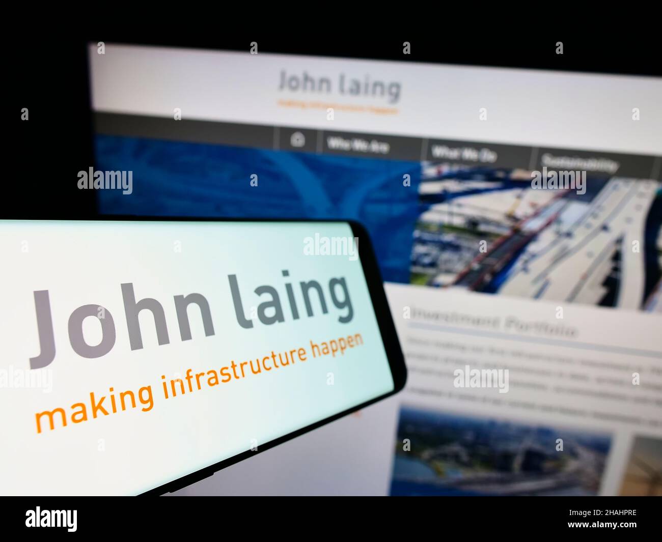 Smartphone with logo of British company John Laing Group Limited on screen in front of business website. Focus on left of phone display. Stock Photo