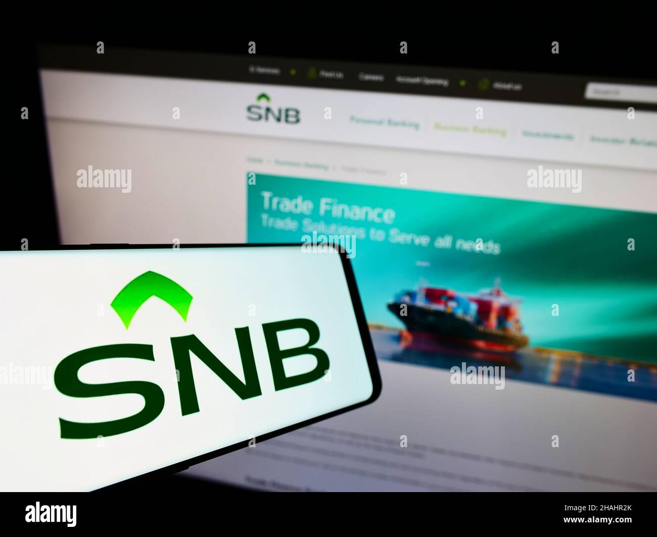 Cellphone with logo of financial company Saudi National Bank (SNB) on screen in front of business website. Focus on center-left of phone display. Stock Photo