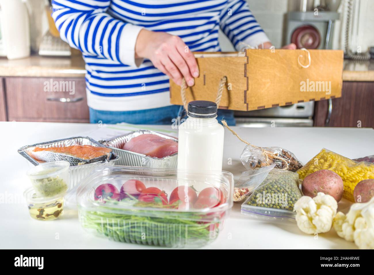 Caucasian woman take apart box with delivery of ingredients, recipes