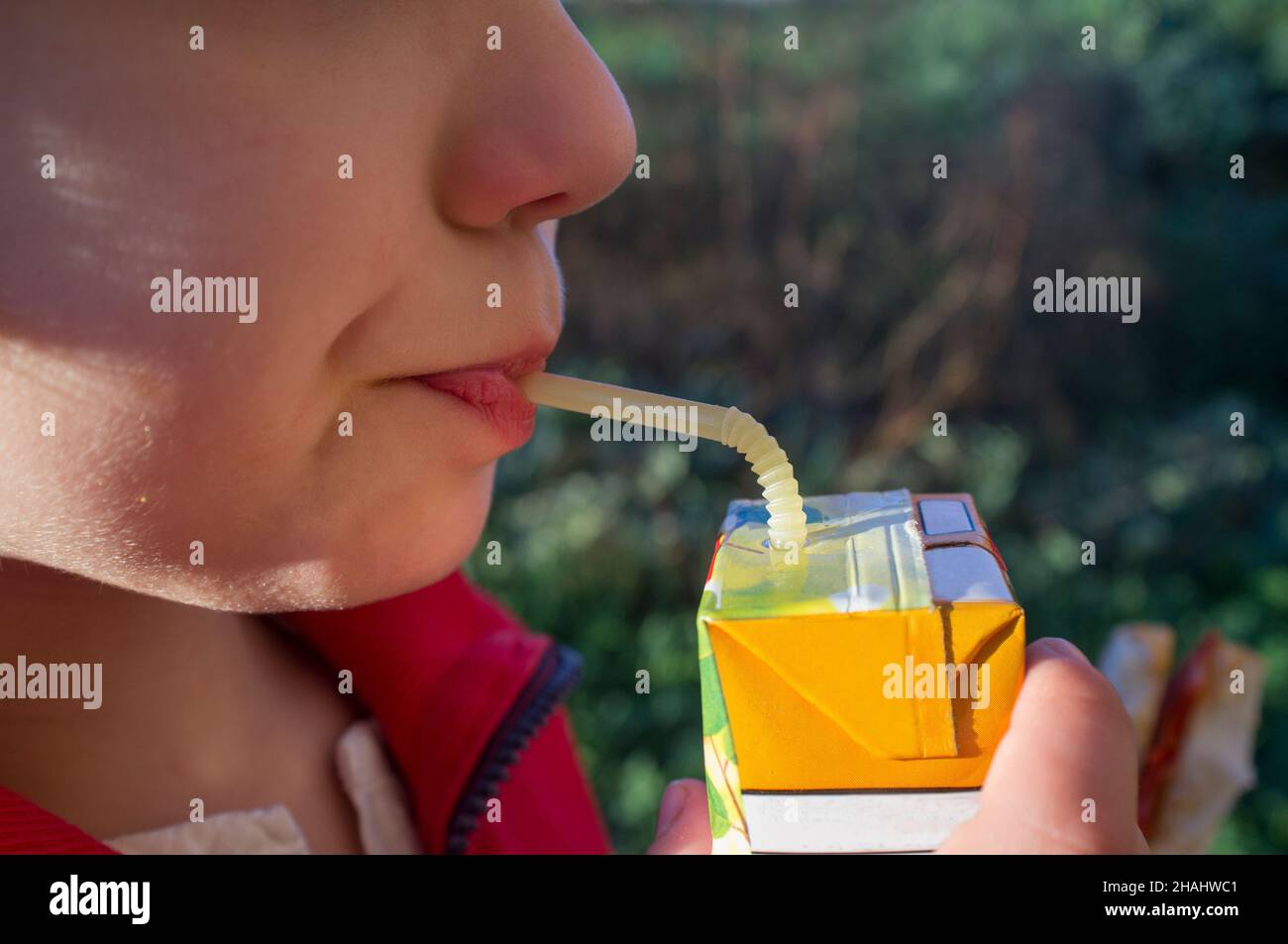 Child boy drinking sweetened juice fruit juice from brick. Fruit juice