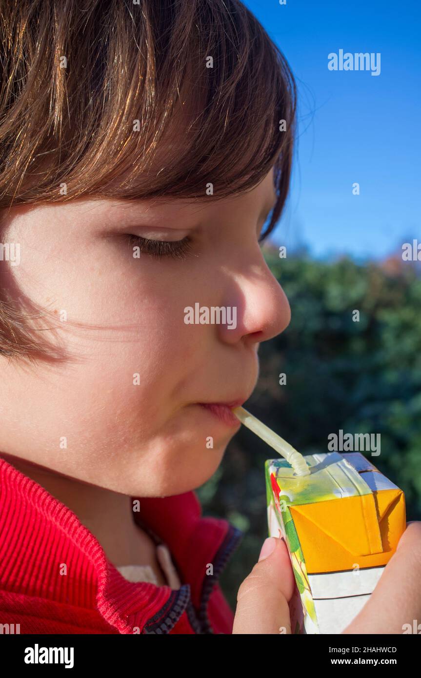 Child boy drinking sweetened juice fruit juice from brick. Fruit juice for children concept Stock Photo