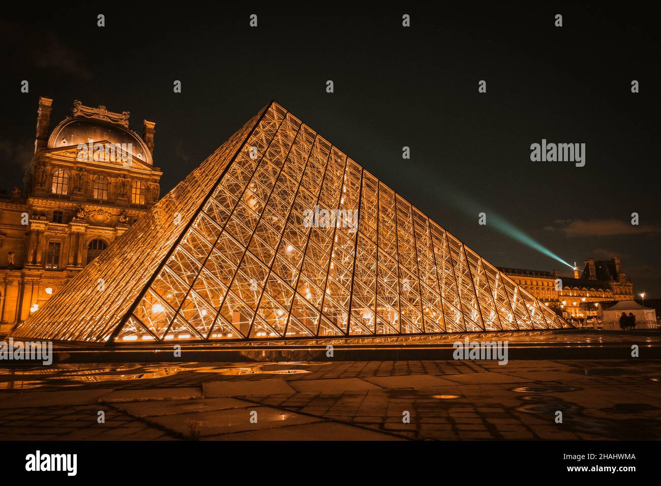 The Louvre Pyramid shines at night in Paris, France. The museum is housed in the Louvre Palace (Palais du Louvre) Stock Photo