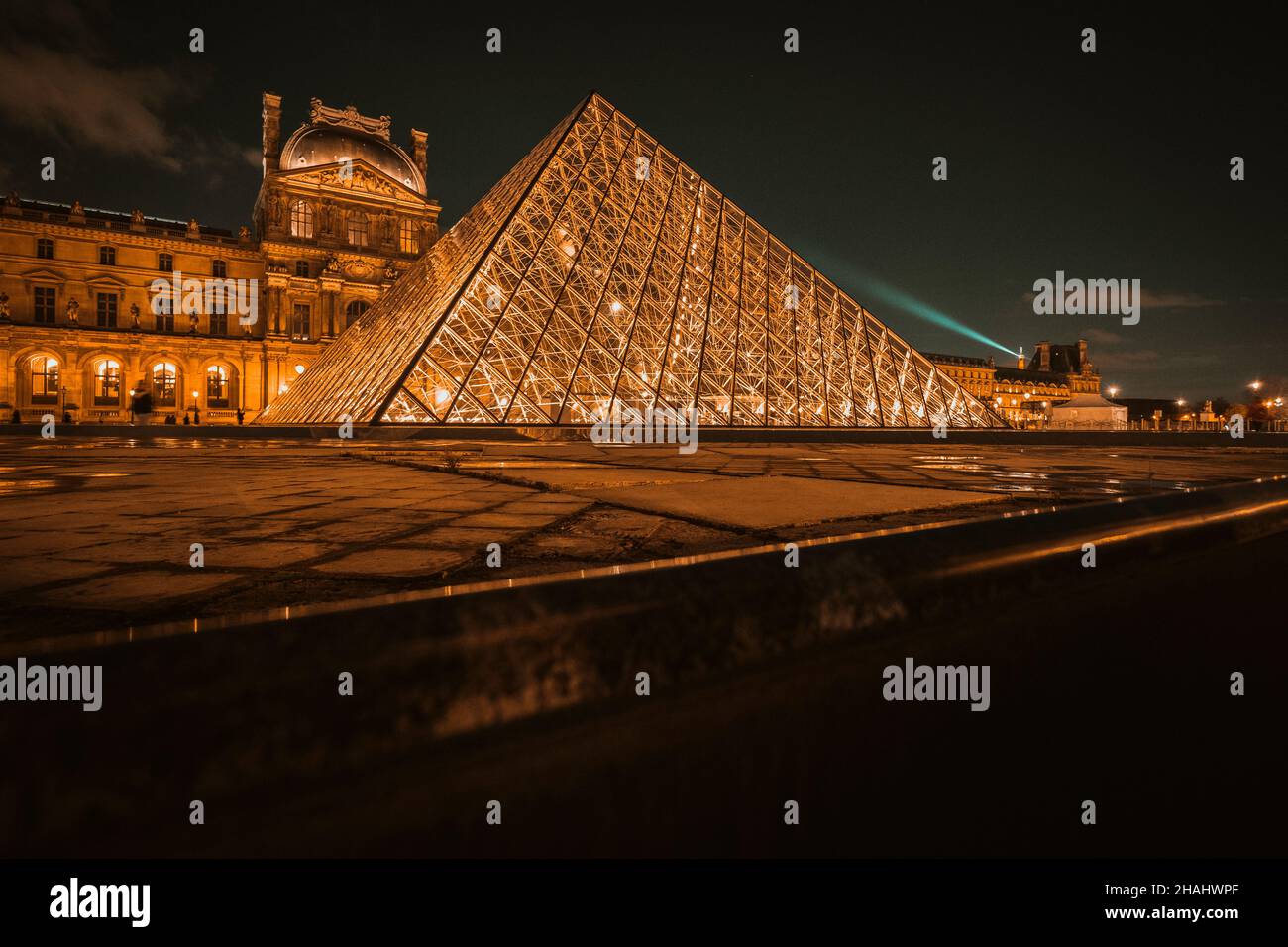 The Louvre Pyramid shines at night in Paris, France. The museum is housed in the Louvre Palace (Palais du Louvre) Stock Photo