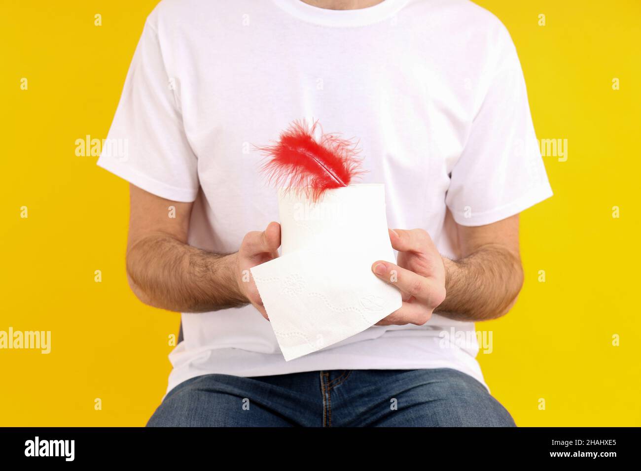 Man sitting on chair on yellow background. Hemorrhoids concept Stock