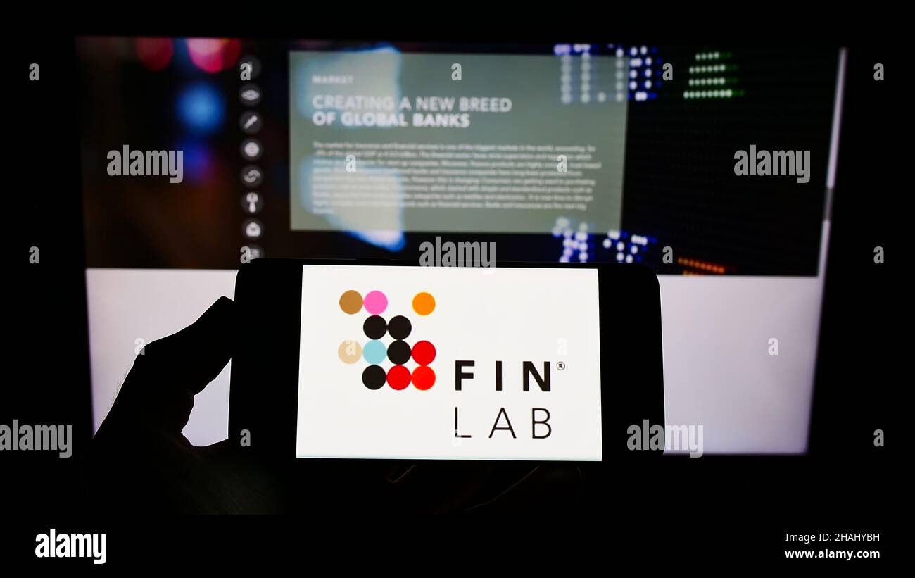 Person holding mobile phone with logo of German investment company ...