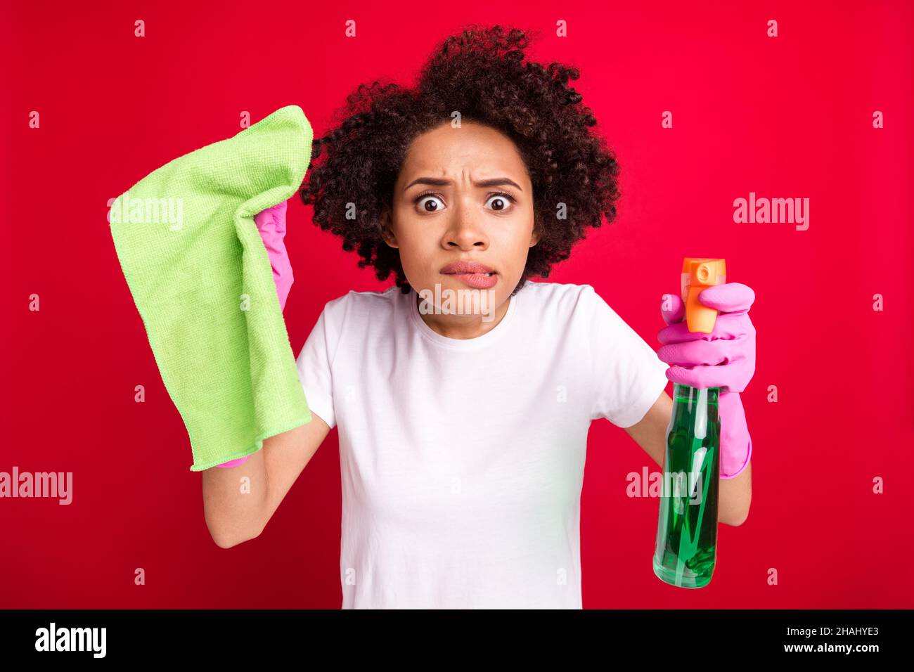 Photo portrait woman biting lip amazed wearing gloves polishing dust isolated vibrant red color background Stock Photo