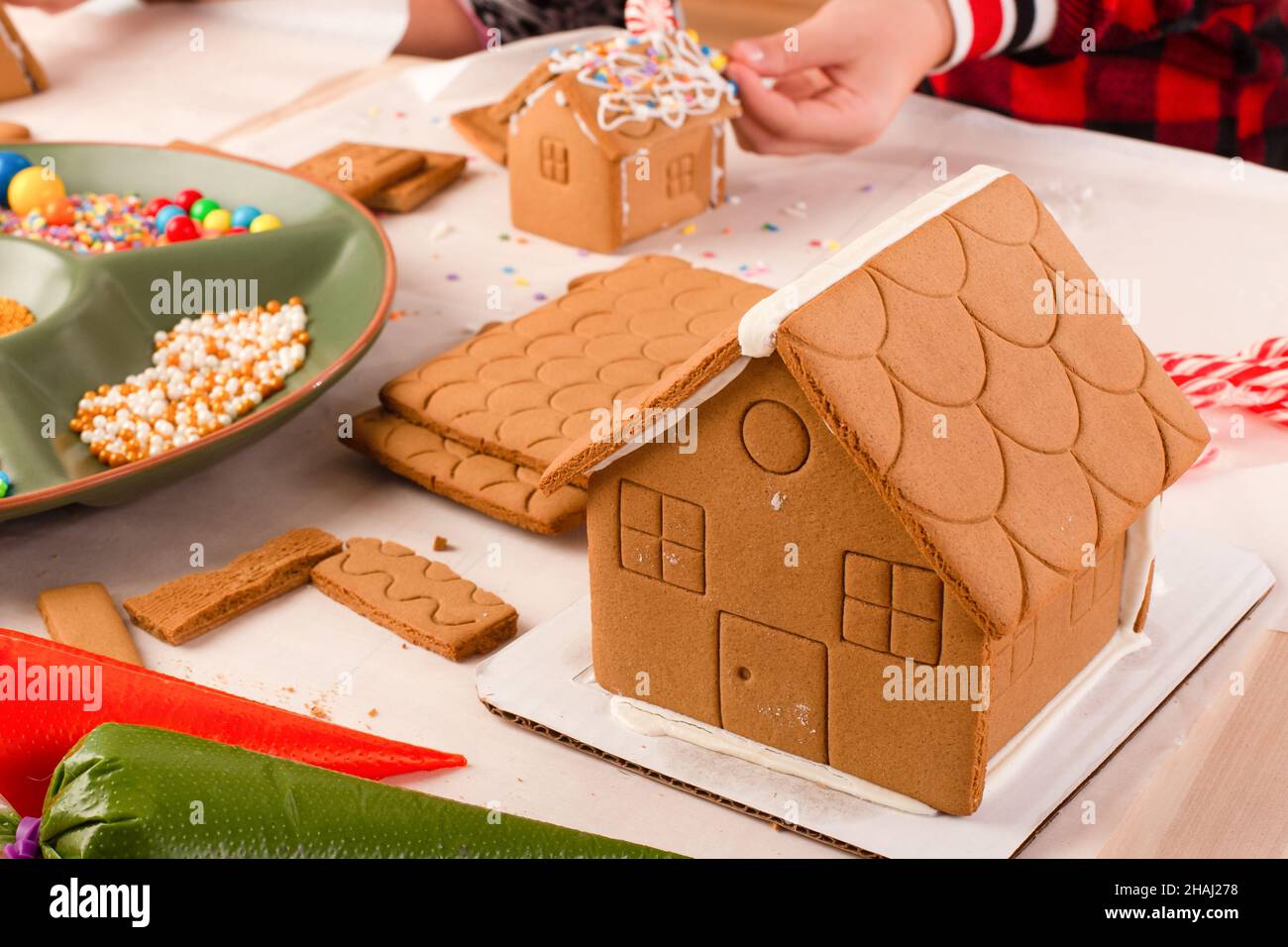 Kids assembling and decorating a gingerbread house at Christmas time. Christmas family tradition, Christmas crafts. Stock Photo