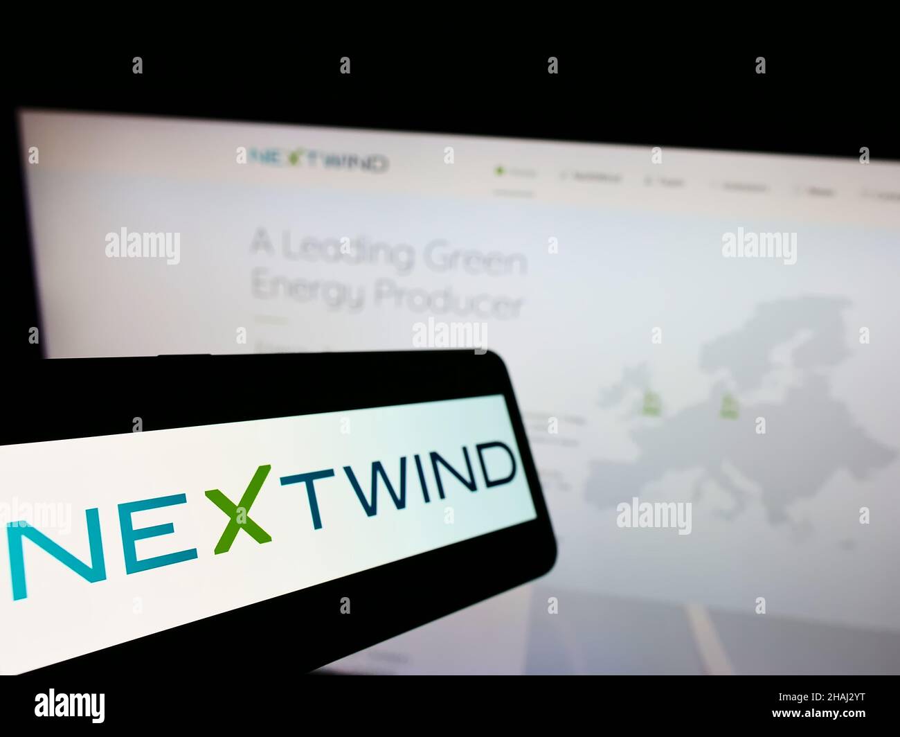 Cellphone with logo of wind energy company NeXtWind Management GmbH on screen in front of business website. Focus on center-left of phone display. Stock Photo