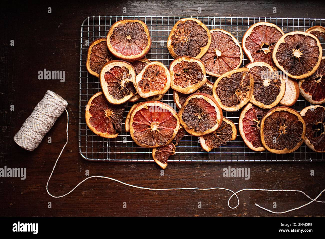 Rows of dried citrus including oranges and grapefruits with roll of natural white string, preparing to make DIY natural holiday garlands Stock Photo