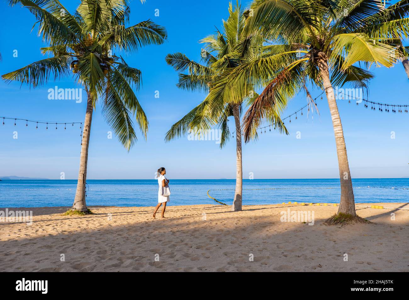 Na Jomtien Beach Pattaya Thailand, white tropical beach during sunset in Pattaya Najomtien. Asian woman walking at the beach with palm trees, tropical beach Stock Photo