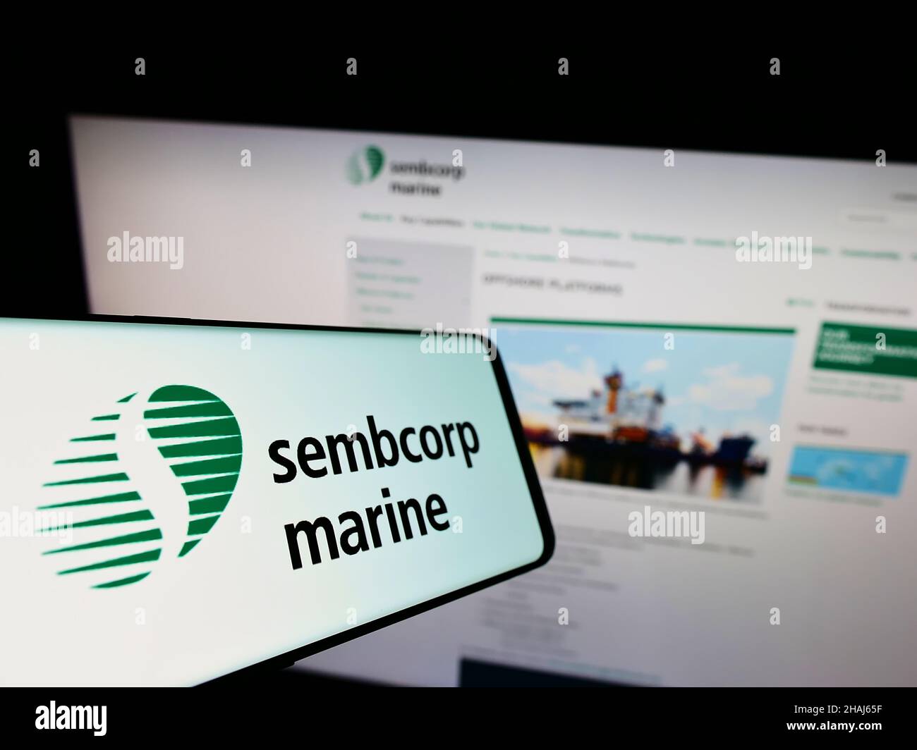 Cellphone with logo of Singaporean company Sembcorp Industries Ltd on screen in front of business website. Focus on center-left of phone display. Stock Photo