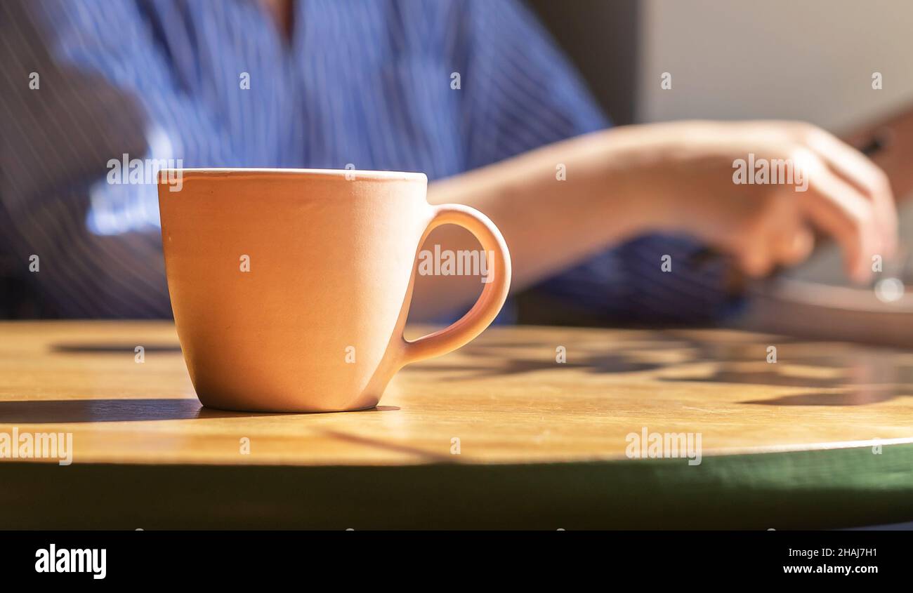 Closeup of coffee cup on wooden desk in cafe with female hands on ...