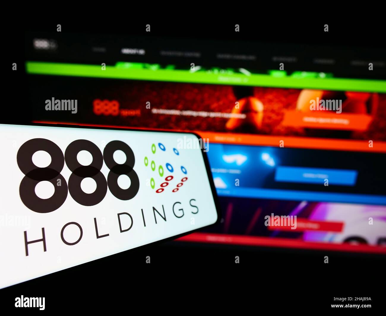 Cellphone with logo of online gambling company 888 Holdings plc on screen in front of business website. Focus on center-left of phone display. Stock Photo