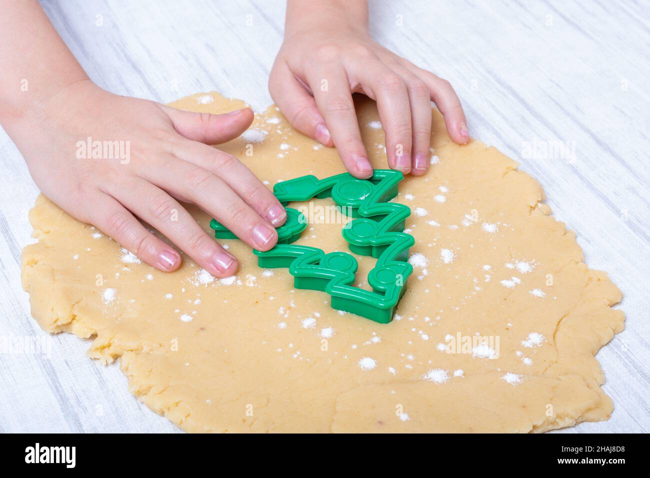 Christmas and New Years tradition. Family home bakery. Cooking traditional gingerbread cookies. Childrens hands cutting raw gingerbread dough cookies Stock Photo
