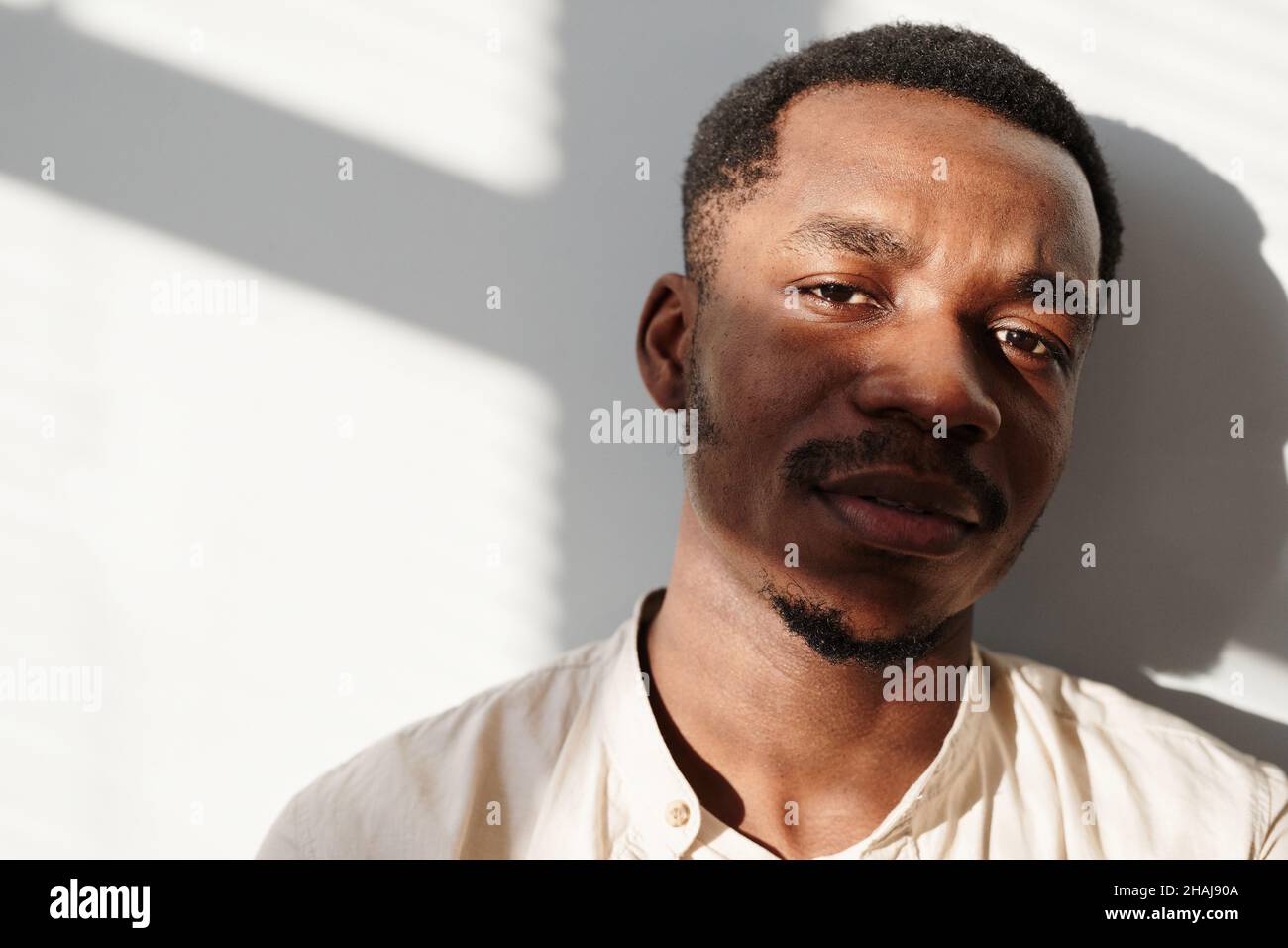 Portrait of African handsome man looking at camera standing against the ...