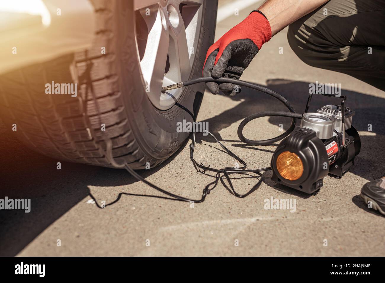 Tire pump inflating car wheel. Tyre inflator in male hands, checking pressure. Stock Photo