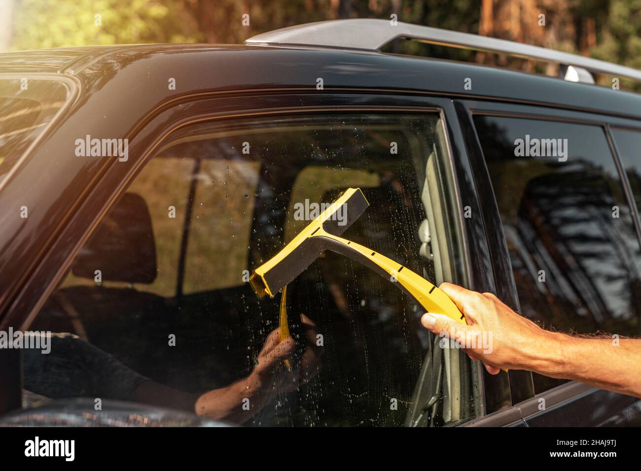 Hand with car rubber scraber clean auto window outside. Stock Photo