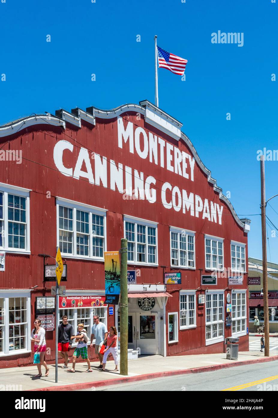 MONTEREY CANNERY ROW RED BOARD BUILDING AMERICAN FLAG Monterey Canning Company iconic building and tourist family Cannery Row Monterey California USA Stock Photo