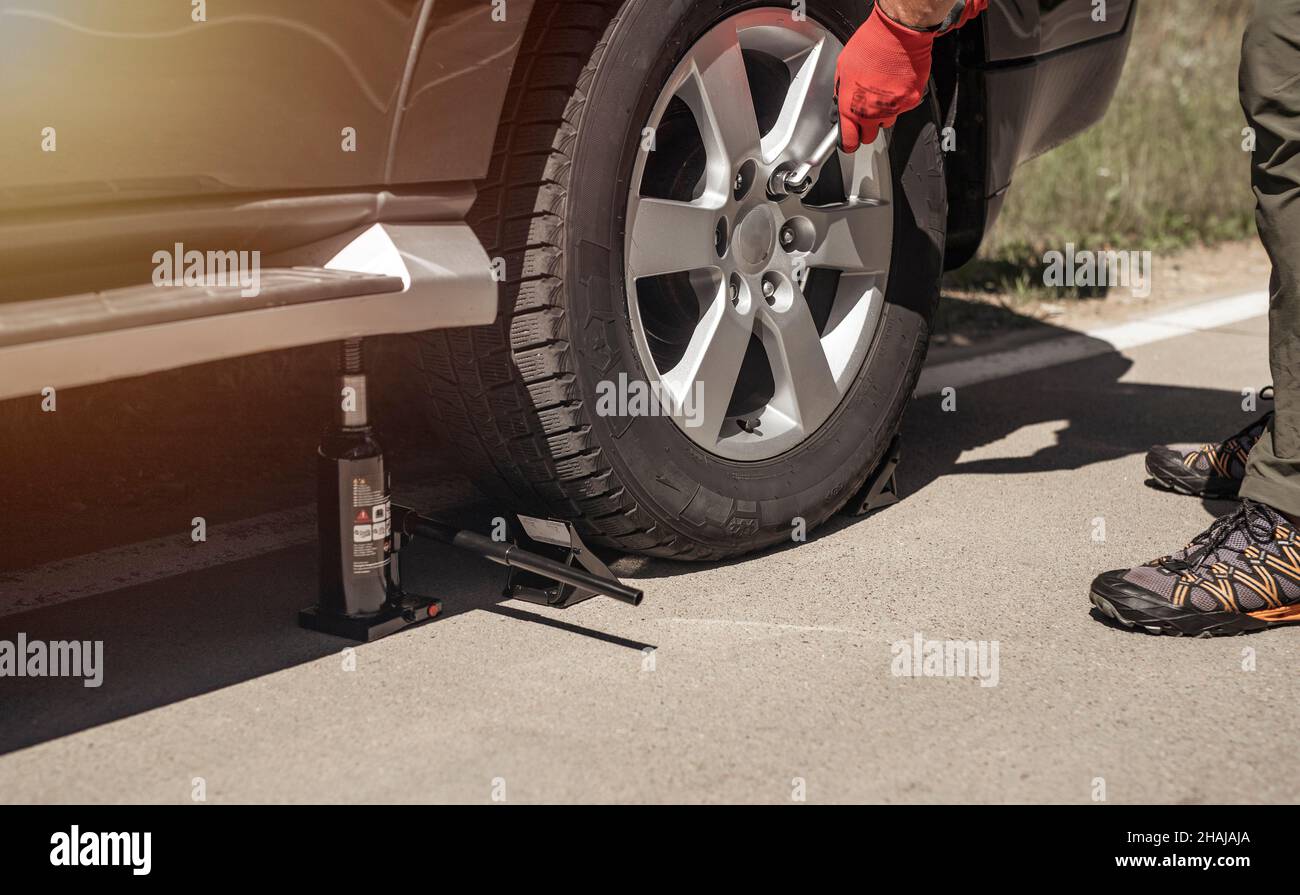 MINSK, BELARUS - October 17 2021 Hydraulic car jack is put under auto by hands in gloves, close up. Stock Photo