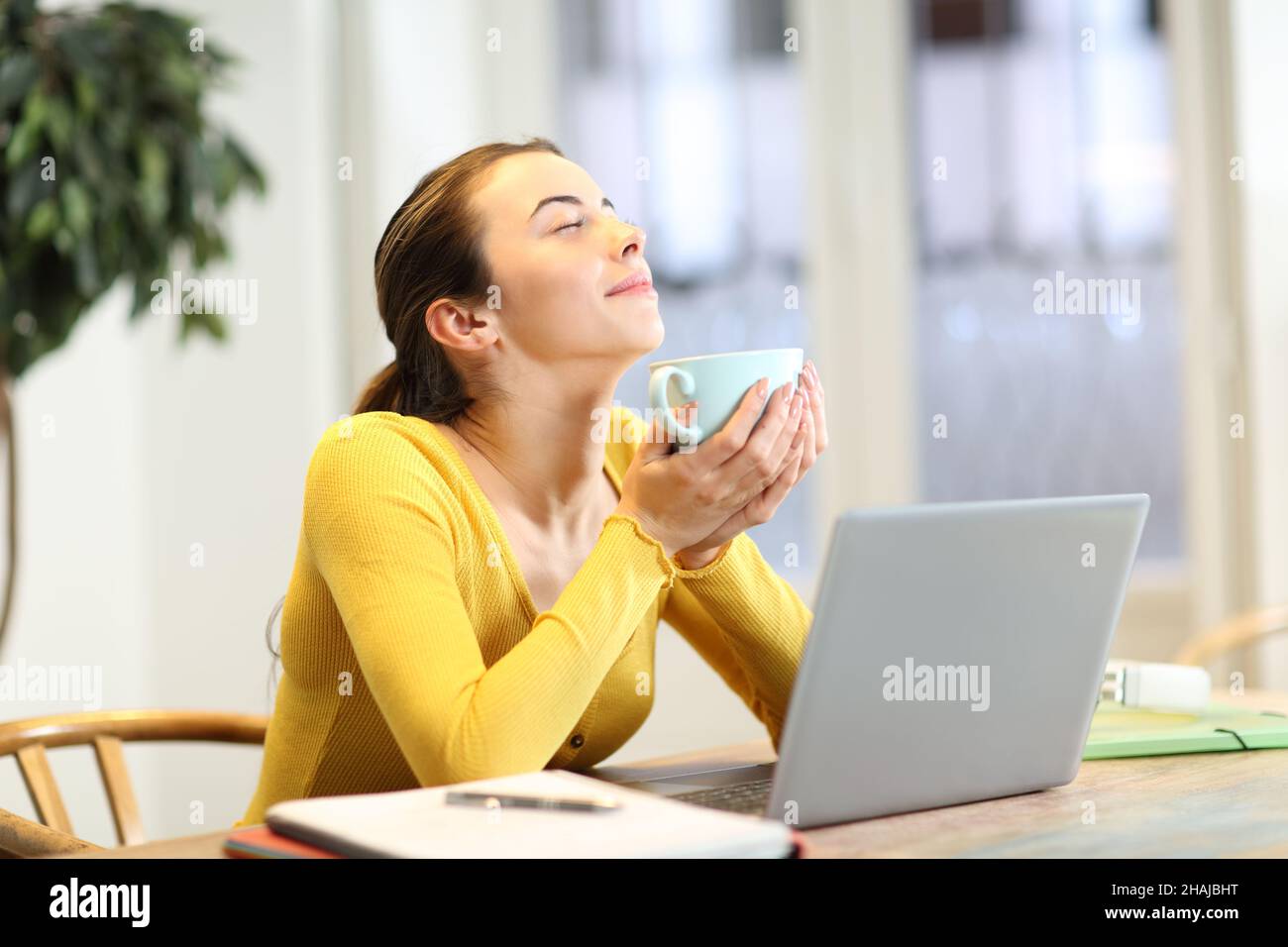 Student resting drinking coffee sitting on a chair at home Stock Photo