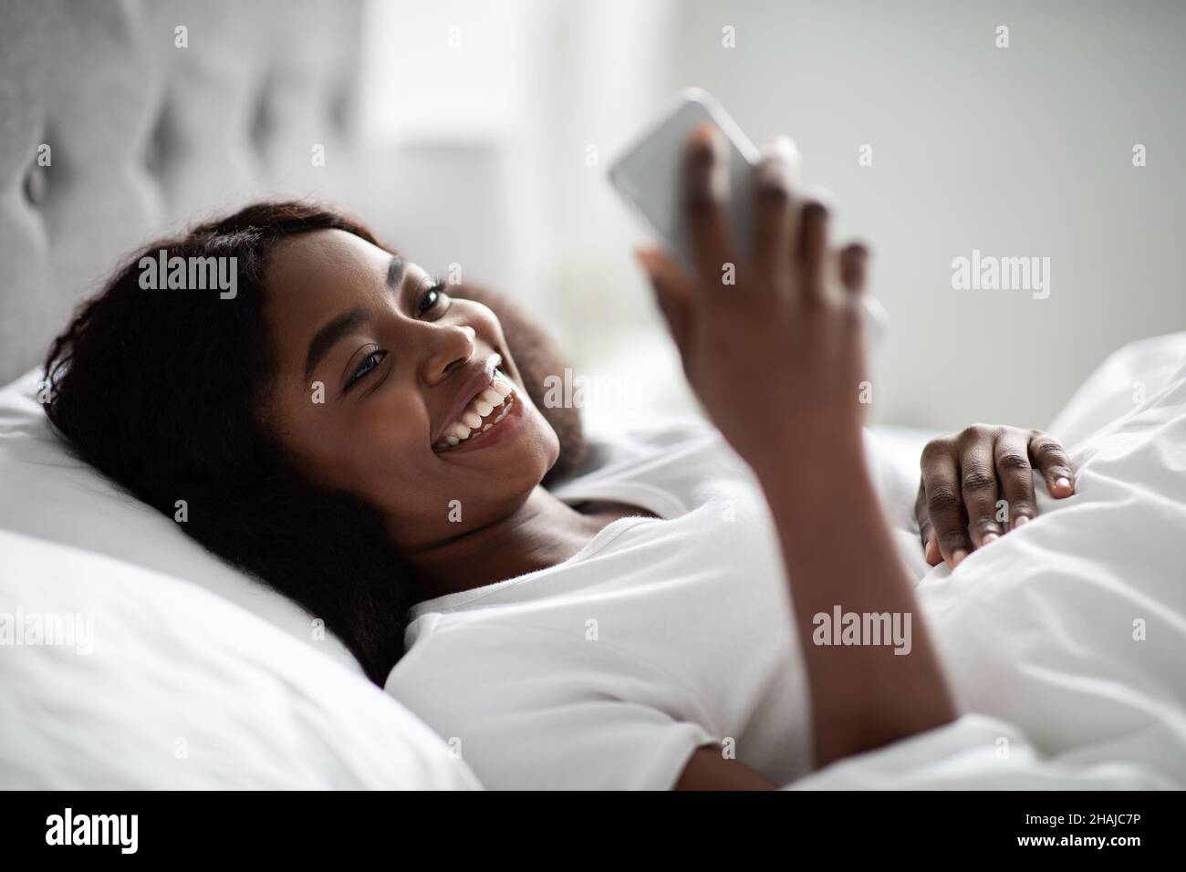 Positive millennial black woman having video call in bed Stock Photo ...
