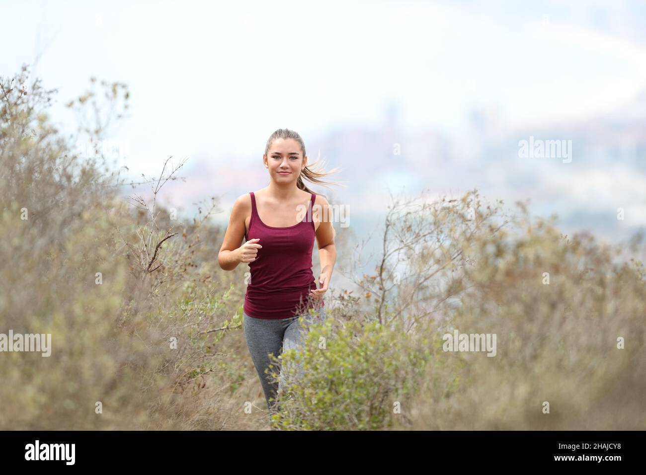 Front view portrait of a happy teen running in the mountain alone Stock Photo