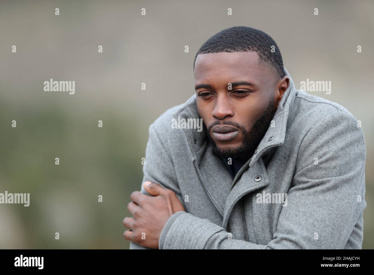 Stressed man with black skin getting cold with a jacket outdoors in winter Stock Photo