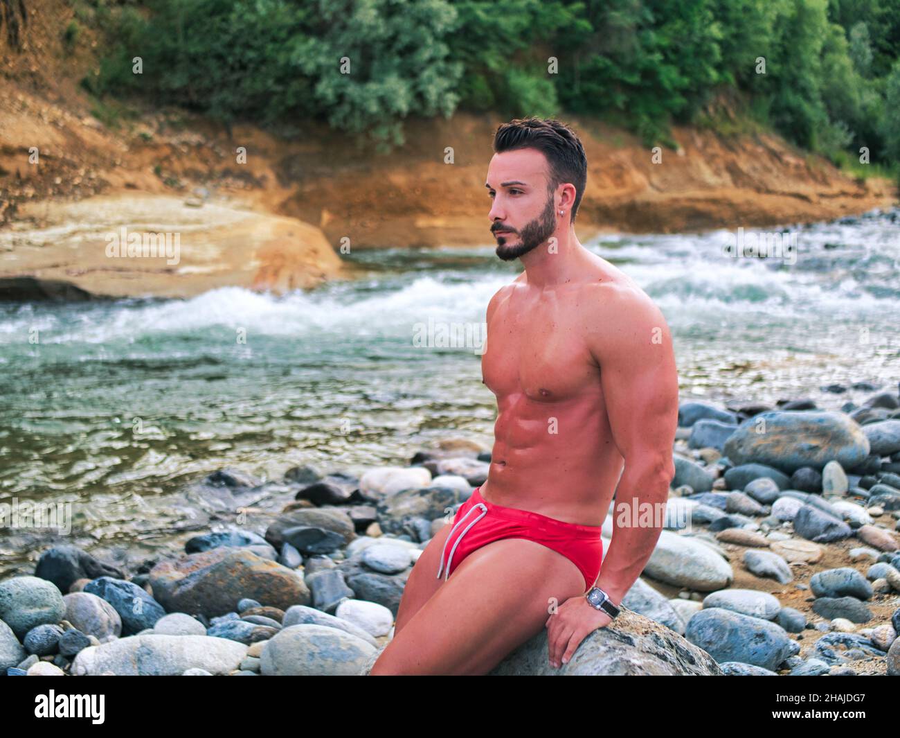 Attractive muscular shirtless young man in nature by river Stock Photo