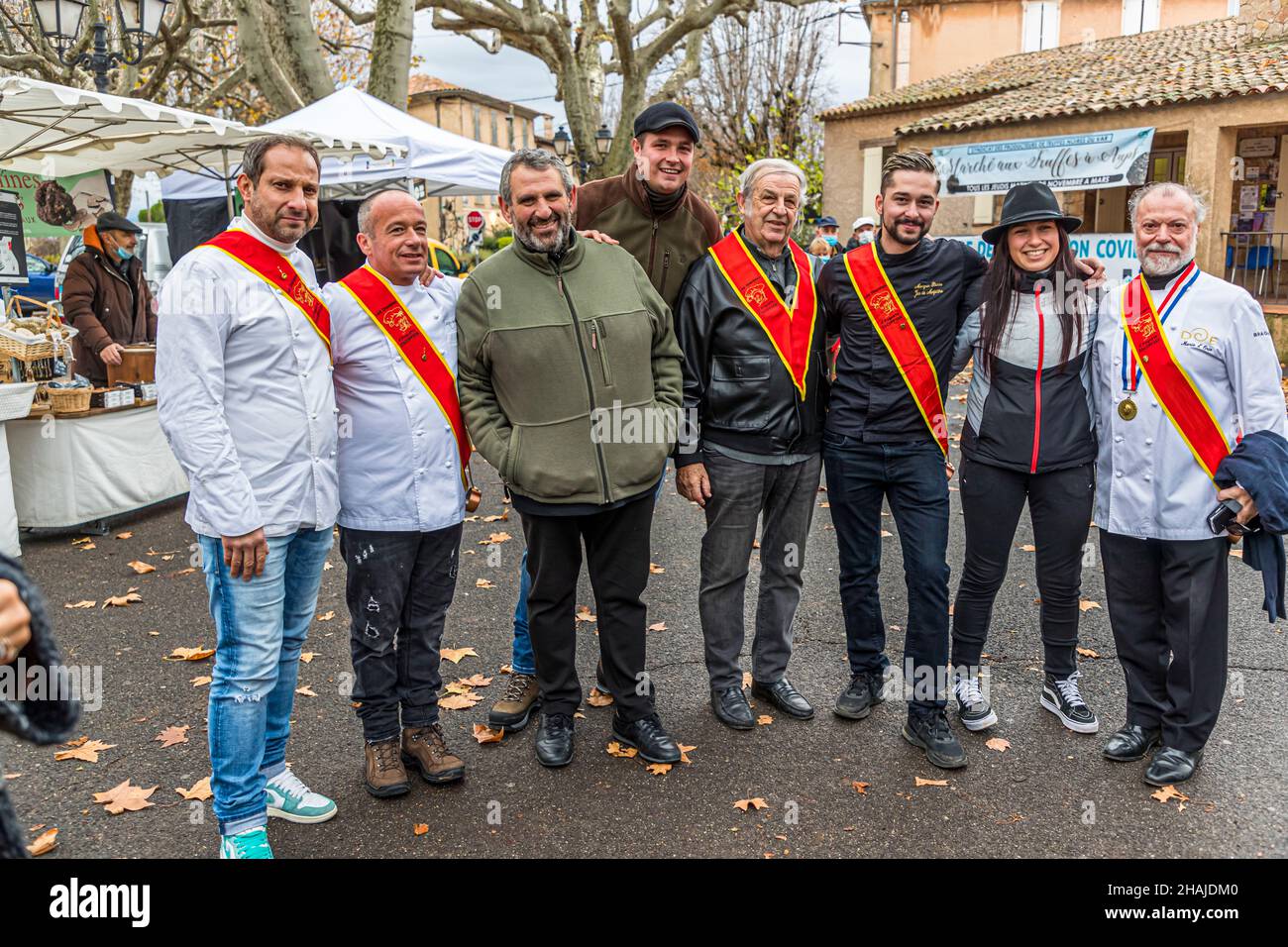 The family of Philippe De Santis stands with members of the truffle syndicate in front of the market stalls at the season opening of the Aups truffle market, Var department, France, traditionally held on the first Thursday of December. Stock Photo