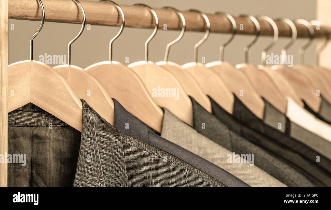 Mens suits in different colors hanging on hanger in a retail clothes