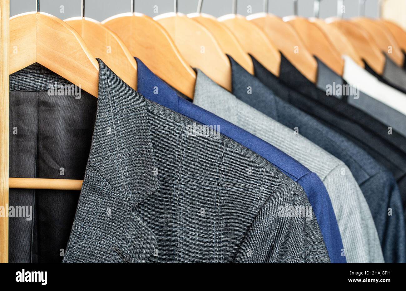 Mens suits in different colors hanging on hanger in a retail clothes