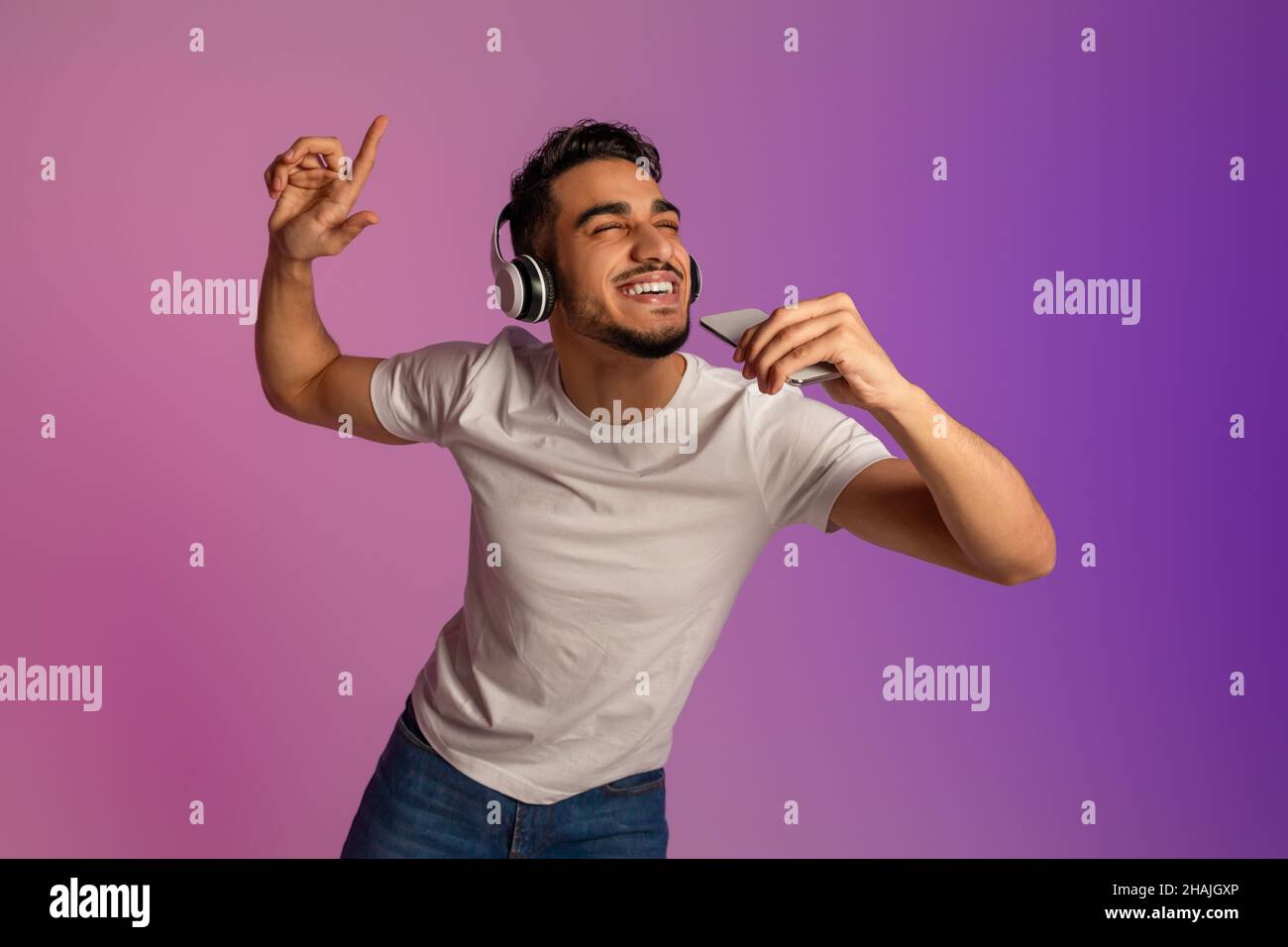 Young Arab man in headphones singing song, using smartphone as mic, enjoying new mobile music app in neon light Stock Photo - Alamy Young Arab man in headphones singing song, using smartphone as mic, enjoying new mobile music app in neon light Stock Photo - Alamy