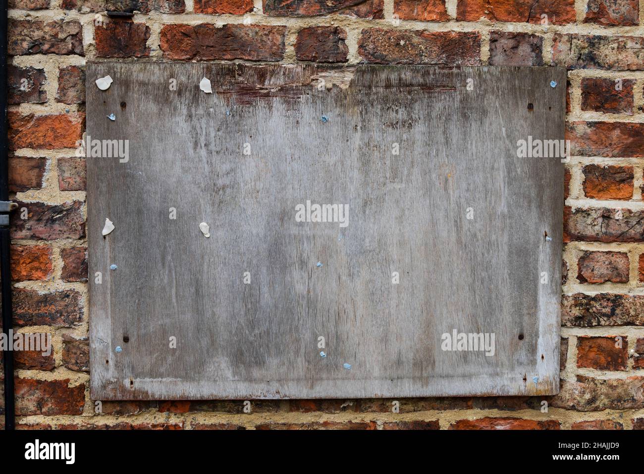 Worn blank wooden sign board on a traditional brick wall. Stock Photo