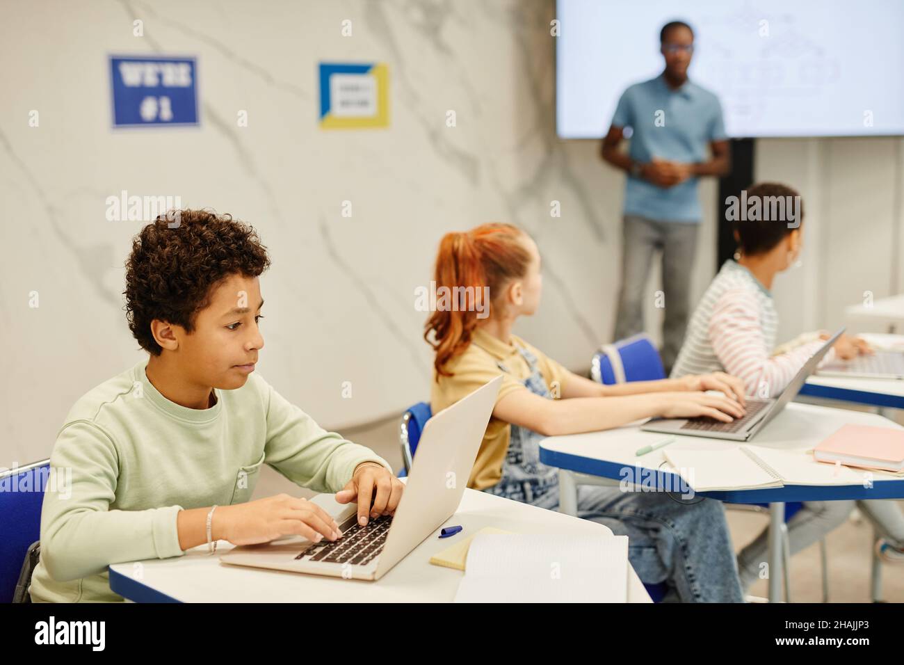 Side view portrait of teenge boy using laptop while studying in modern ...