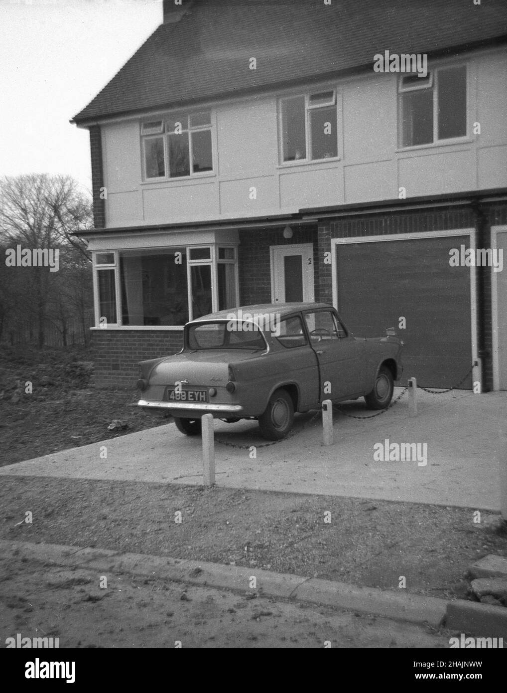 1963, historical, a Ford Anglia car of the era parked on a driveway of a recently constructed end of terraced, two-storey, semi-detached house on a new modern housing estate, Essex, England. UK Stock Photo