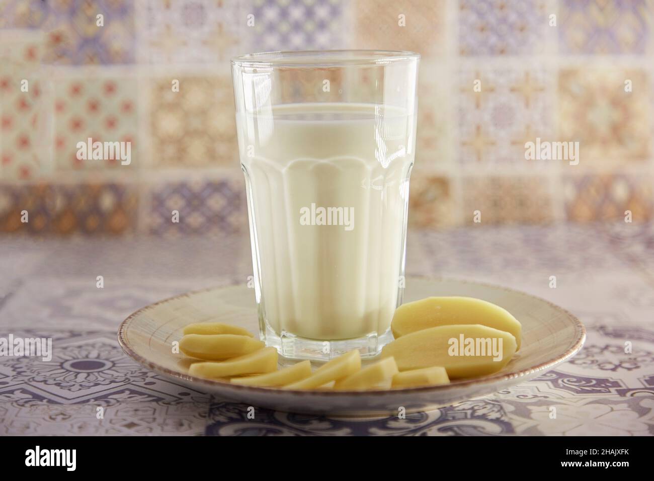 Lactose free, environment friendly potato milk and potato on the plate on the table. Alternative, non-dairy milk. Tile classic background. Copy space. Stock Photo