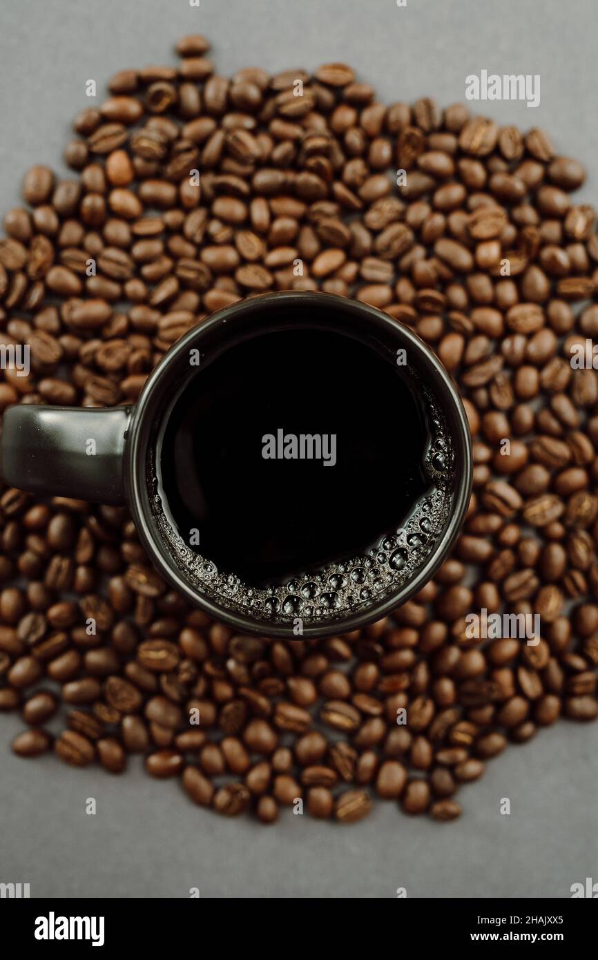 Close up of Dark Coffee Mug with Black Coffee and Coffee Beans on Dark Background Stock Photo