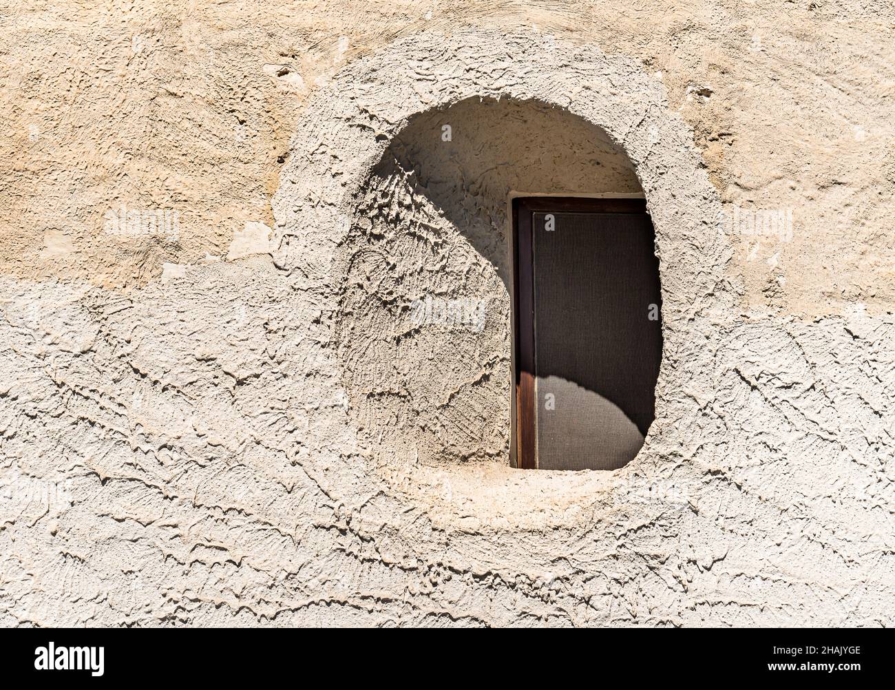 Little round window inside the stone wall of the typical old mediterranean house in Sicily. Stock Photo