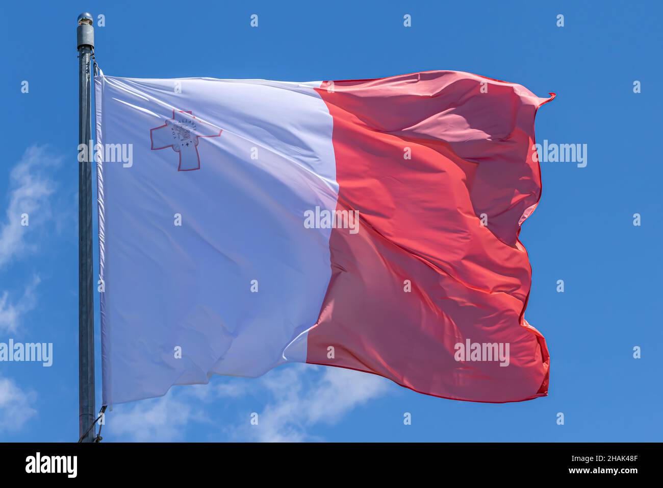 Maltese national flag waving on blue sky background. Republic of Malta, MT Stock Photo