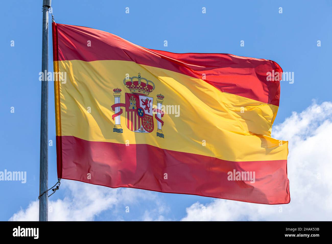 Spanish national flag waving on blue sky background. Kingdom of Spain, ESP Stock Photo