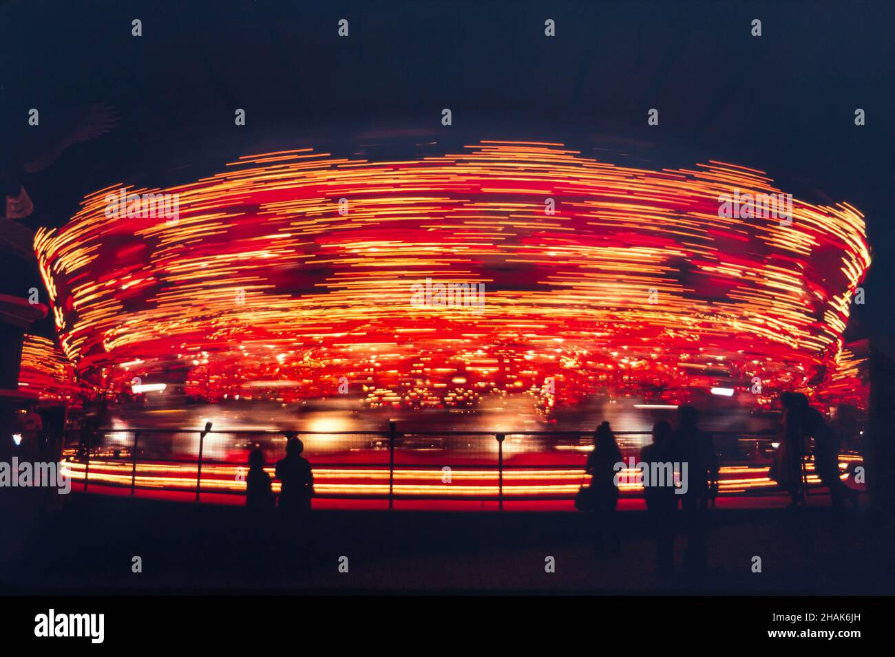 A whirling merry-to-round amusement ride spinning in bright colors at night. Stock Photo