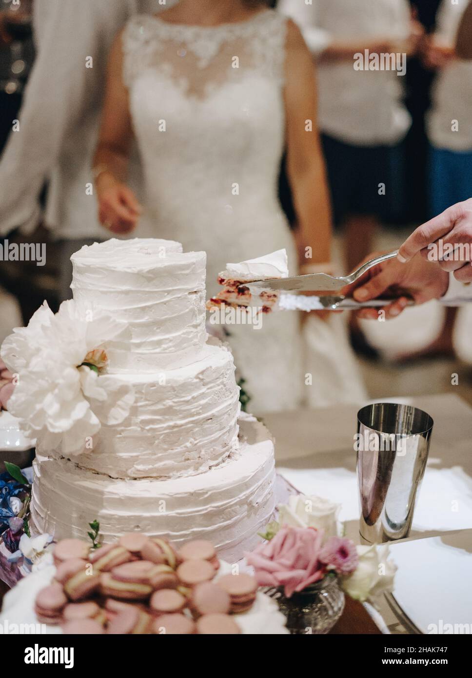 Cutting a white wedding three-tiered cake Stock Photo - Alamy